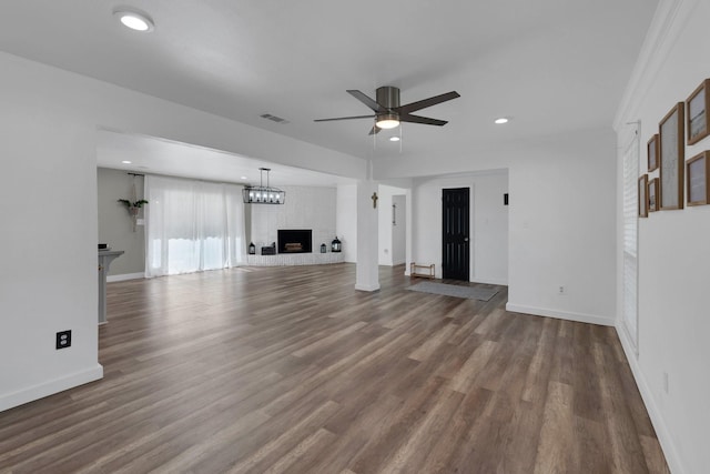 unfurnished living room with visible vents, a brick fireplace, dark wood-type flooring, and a ceiling fan