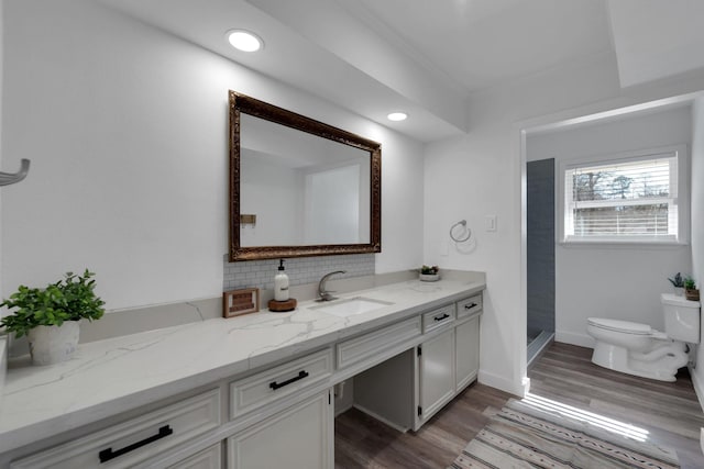 bathroom with toilet, tasteful backsplash, wood finished floors, baseboards, and vanity