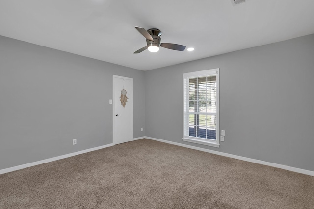 carpeted spare room featuring a ceiling fan and baseboards