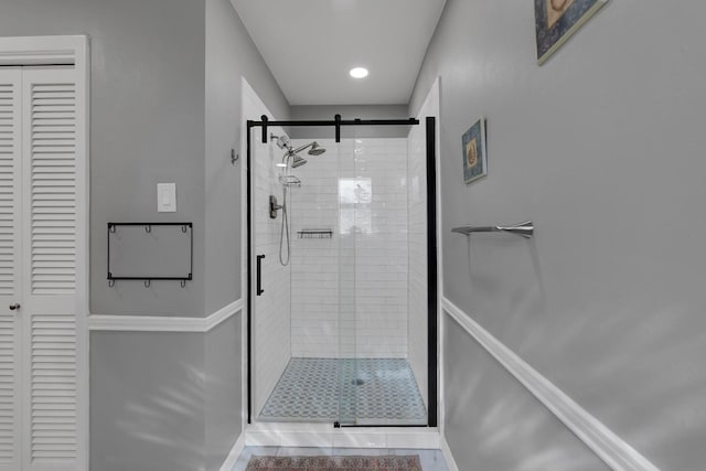 bathroom with tile patterned flooring, a shower stall, baseboards, and a closet