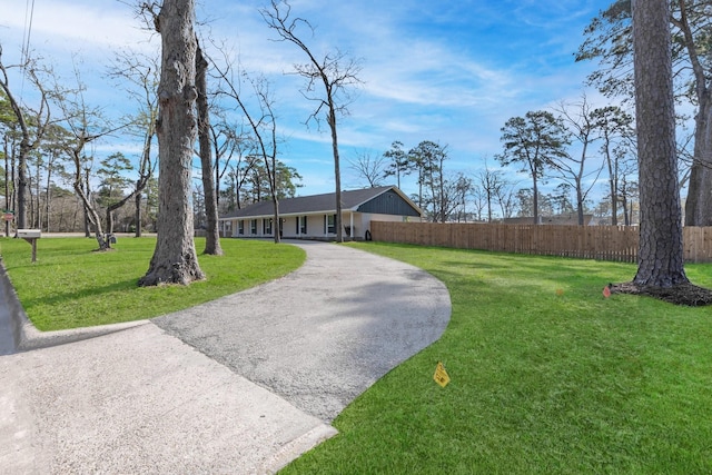 view of front of house with aphalt driveway, a front lawn, and fence