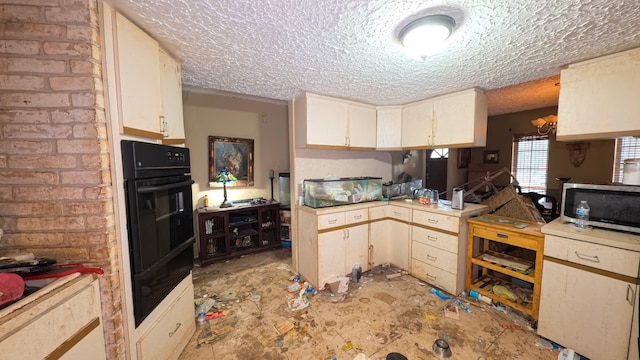 kitchen featuring a textured ceiling, light countertops, dobule oven black, white cabinetry, and stainless steel microwave