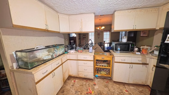 kitchen featuring light countertops, a textured ceiling, white cabinetry, stainless steel microwave, and a chandelier