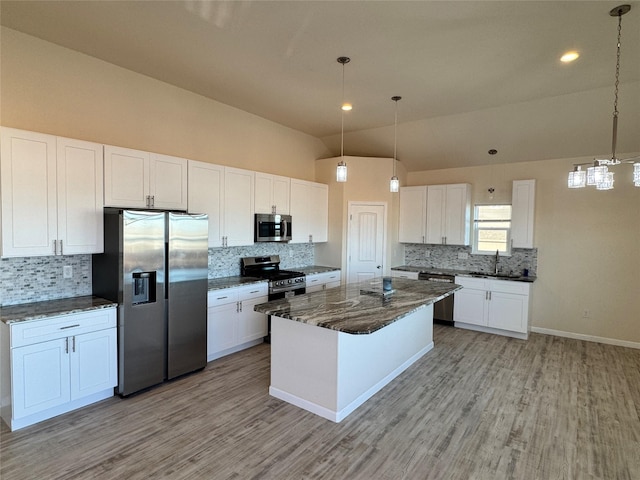 kitchen with light wood-type flooring, lofted ceiling, white cabinets, stainless steel appliances, and a sink