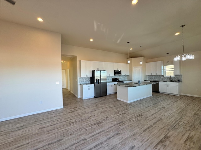 kitchen featuring tasteful backsplash, open floor plan, white cabinetry, appliances with stainless steel finishes, and light wood finished floors