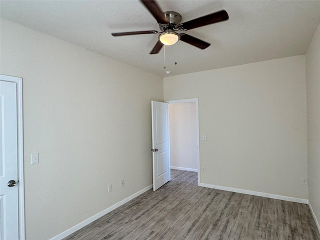 empty room with a ceiling fan, baseboards, and wood finished floors