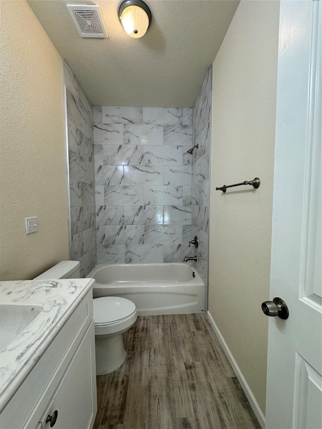 bathroom with visible vents, toilet, wood finished floors, a textured ceiling, and  shower combination