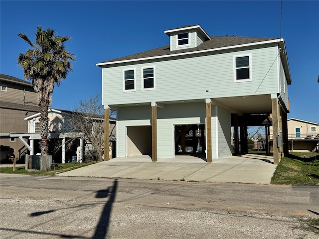 view of front facade with a carport, concrete driveway, a garage, and a shingled roof