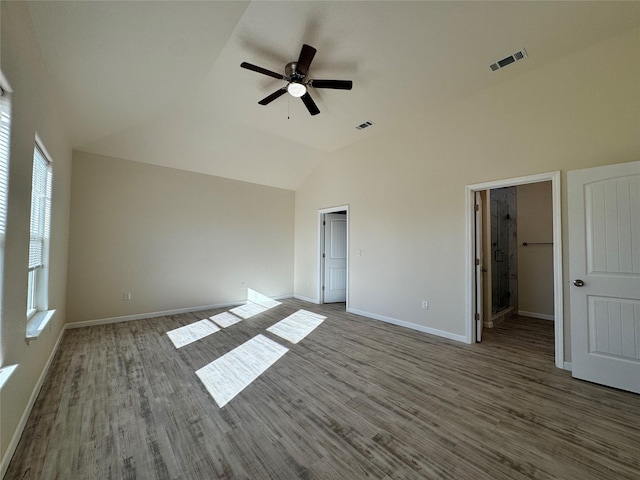 spare room with baseboards, wood finished floors, visible vents, and high vaulted ceiling