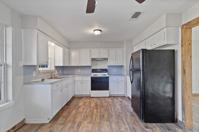 kitchen featuring visible vents, white electric range, a sink, freestanding refrigerator, and light countertops