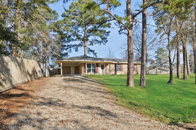 view of front of property featuring brick siding, driveway, a front lawn, and fence