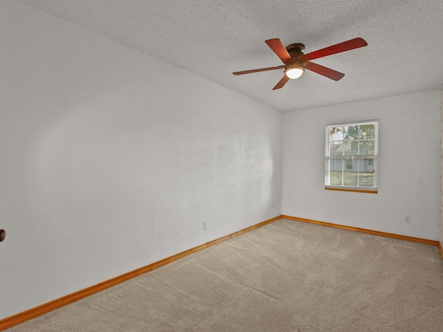 carpeted spare room with ceiling fan, a textured ceiling, and baseboards