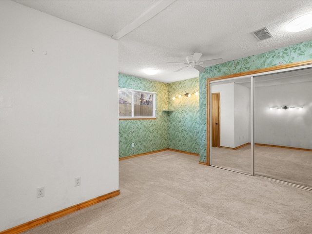 unfurnished bedroom featuring wallpapered walls, baseboards, visible vents, and a textured ceiling