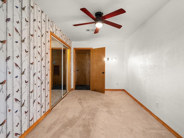 carpeted spare room with visible vents, baseboards, a textured ceiling, and a ceiling fan