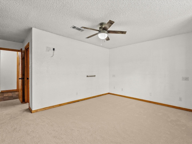 carpeted empty room with visible vents, baseboards, a textured ceiling, and a ceiling fan