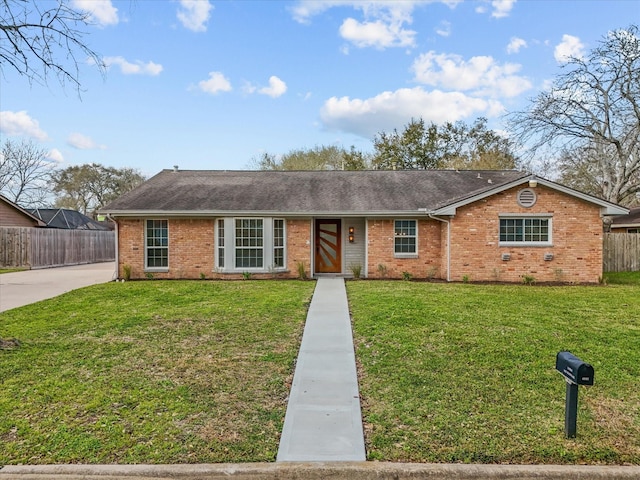 ranch-style house featuring brick siding, roof with shingles, a front yard, and fence