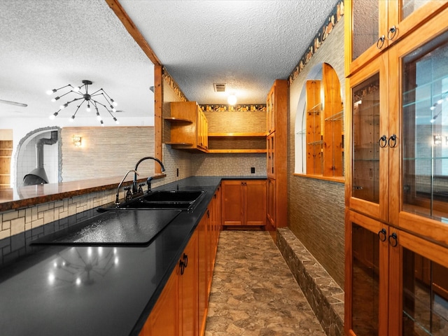 kitchen featuring visible vents, brown cabinets, a sink, open shelves, and dark countertops