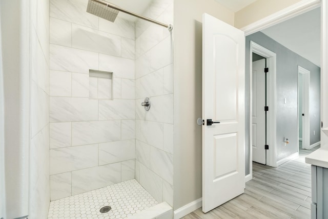 full bathroom featuring wood finished floors, baseboards, and tiled shower