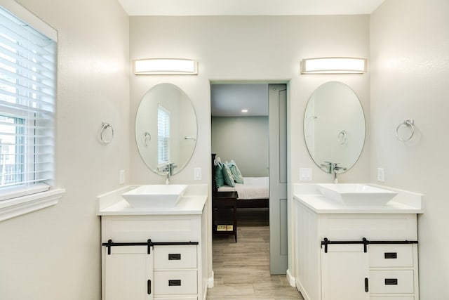 bathroom featuring ensuite bath, two vanities, and a sink