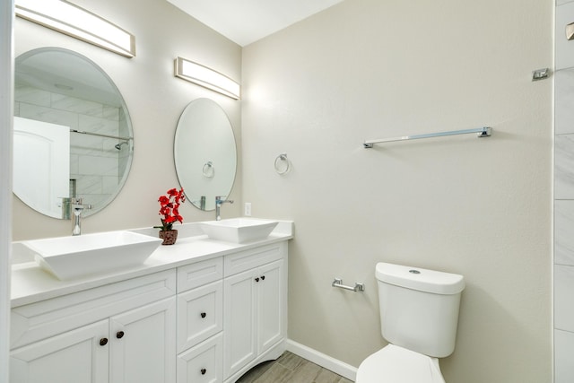 bathroom with toilet, wood finished floors, baseboards, and a sink