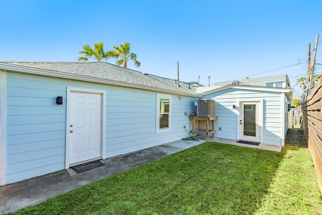 back of property featuring a patio area, a lawn, roof with shingles, and fence