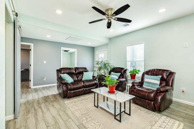 living room featuring a ceiling fan, wood finished floors, visible vents, and baseboards