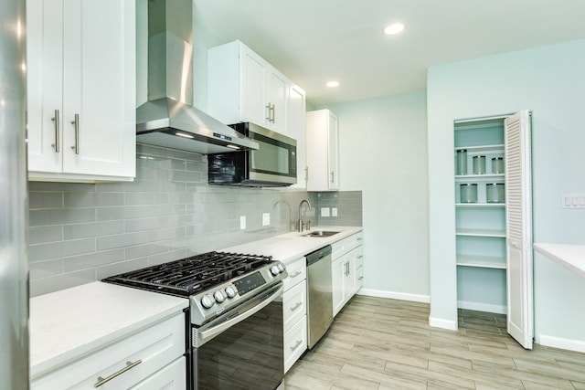 kitchen with backsplash, wall chimney range hood, light countertops, stainless steel appliances, and a sink