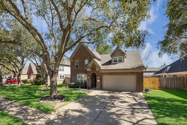 traditional home featuring a front yard, fence, driveway, an attached garage, and brick siding