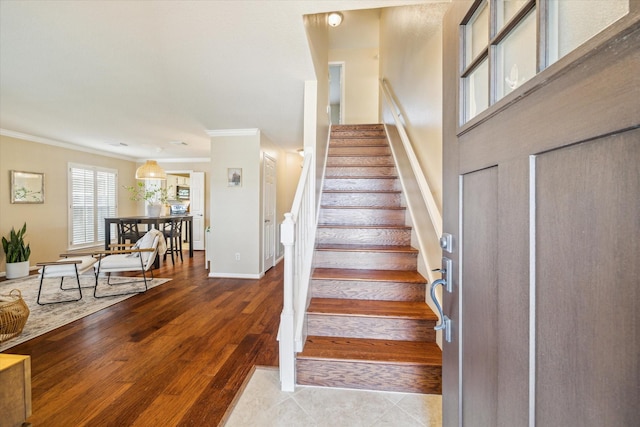 stairway with crown molding, wood finished floors, and baseboards