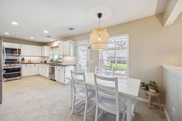 kitchen featuring plenty of natural light, baseboards, backsplash, and stainless steel appliances