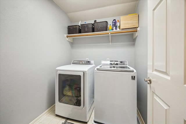 washroom with light tile patterned floors, laundry area, independent washer and dryer, and baseboards