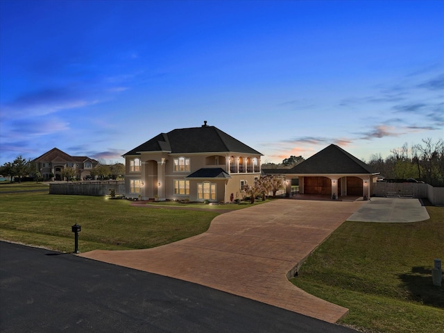 french country style house with stucco siding, driveway, fence, and a lawn