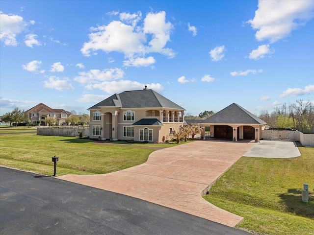 french country style house featuring decorative driveway, a front lawn, fence, an attached carport, and stucco siding