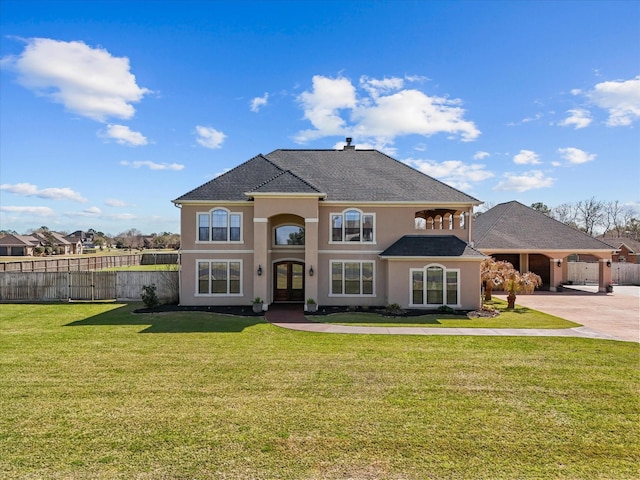 french country inspired facade featuring french doors, a front lawn, concrete driveway, fence, and stucco siding