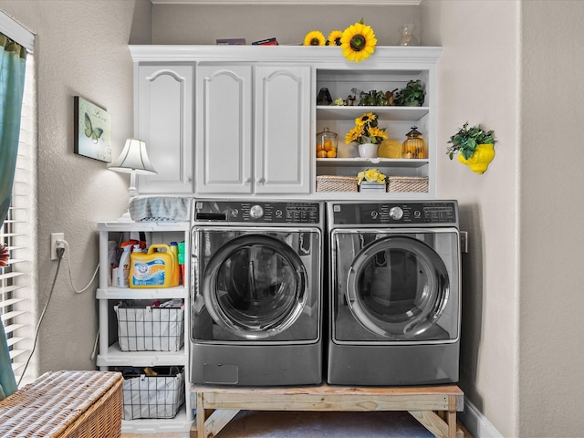 laundry area featuring cabinet space, independent washer and dryer, a textured wall, and baseboards