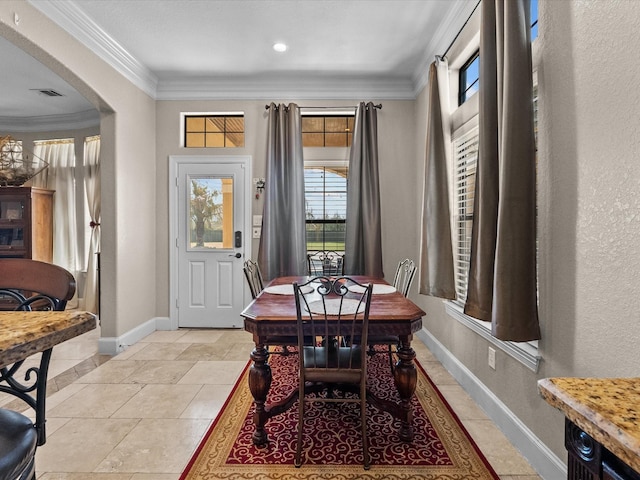 dining space featuring arched walkways, visible vents, crown molding, and baseboards