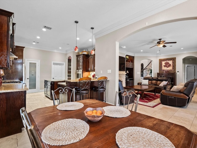 dining area featuring light tile patterned floors, a ceiling fan, recessed lighting, arched walkways, and stairs