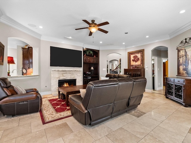 living area featuring recessed lighting, baseboards, a stone fireplace, and ornamental molding