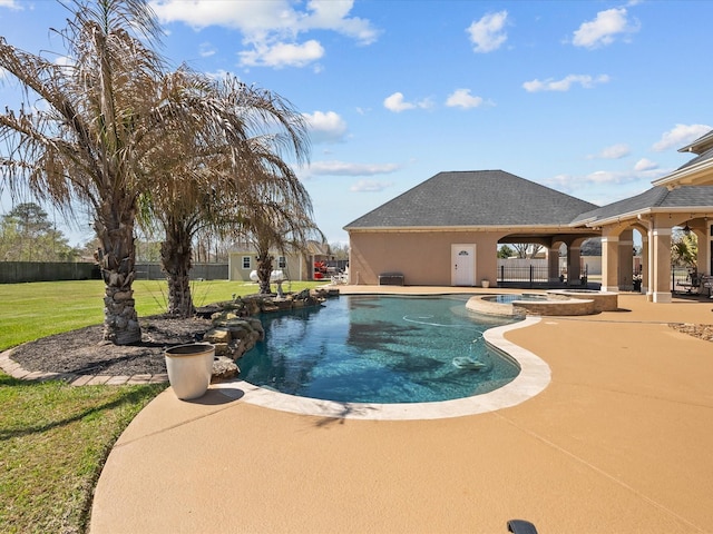 view of swimming pool with fence, a lawn, a pool with connected hot tub, and a patio area