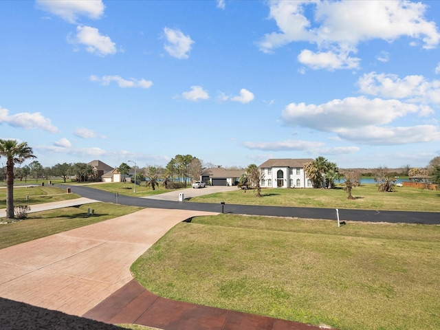 surrounding community featuring a lawn and concrete driveway