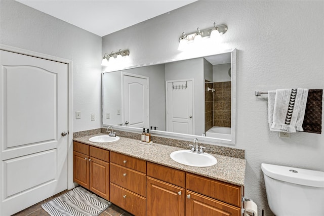 bathroom with double vanity, toilet, and a sink