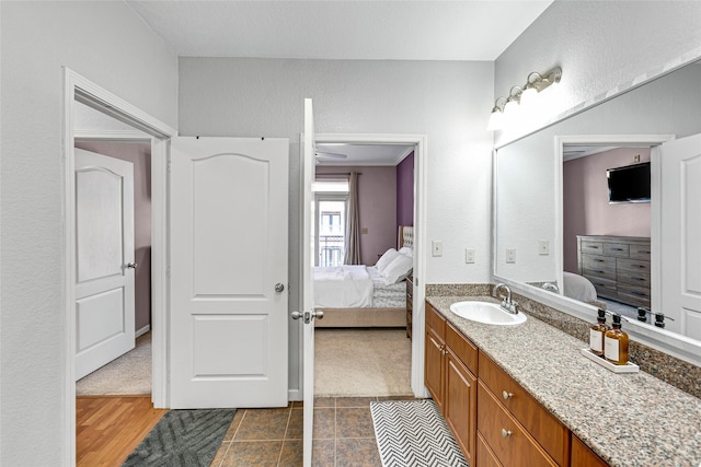 full bathroom featuring vanity, ensuite bath, and a textured wall