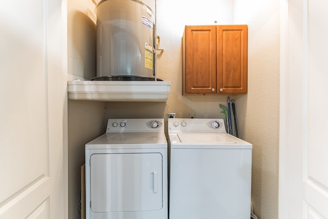 laundry room featuring cabinet space, water heater, a textured wall, and washer and clothes dryer