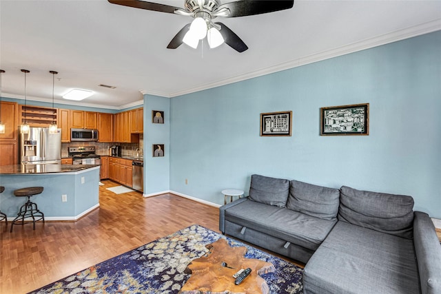 living area featuring ceiling fan, baseboards, light wood-style flooring, and ornamental molding