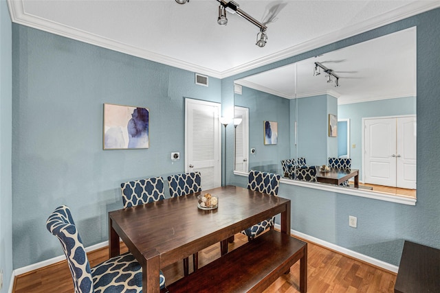 dining area with visible vents, baseboards, wood finished floors, and ornamental molding