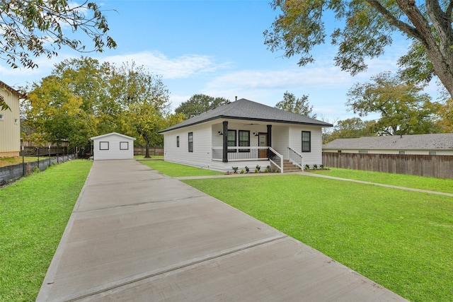 bungalow featuring ceiling fan, a front lawn, fence, a storage shed, and an outdoor structure