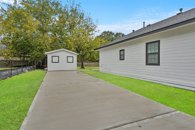 exterior space featuring an outbuilding, a lawn, a fenced backyard, and a shingled roof