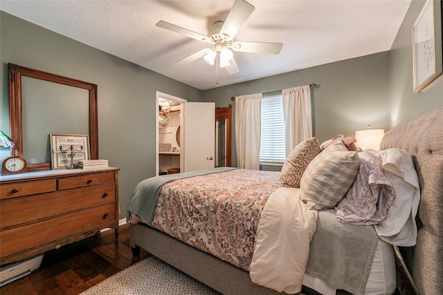 bedroom with dark wood-type flooring, a ceiling fan, and a textured ceiling