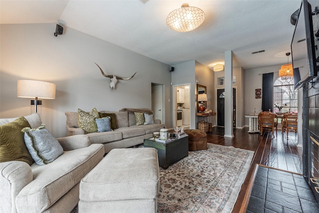 living area with visible vents, baseboards, dark wood-style floors, and vaulted ceiling