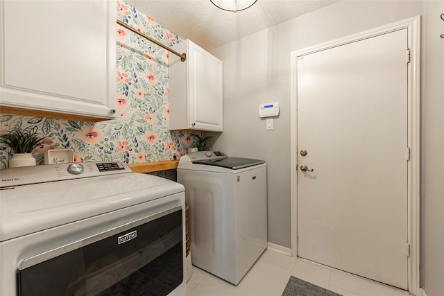 clothes washing area featuring baseboards, light tile patterned flooring, cabinet space, a textured ceiling, and independent washer and dryer